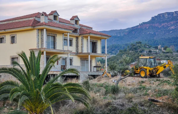 Şantiye ile bitmemiş yeni ev ve sarı Ekskavatör.