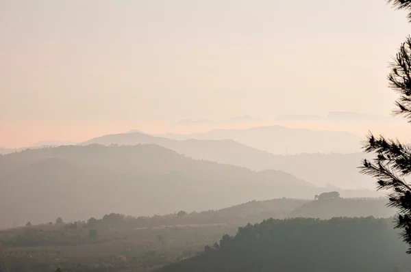 Montañas cubiertas de niebla pesada al atardecer . Fotos de stock libres de derechos