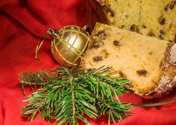 Cut panettone, branch of fir tree, golden bauble. Christmas theme. — Stock Photo, Image