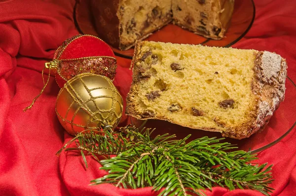 Cut panettone, branch of pine tree and baubles. Christmas theme. — Stock Photo, Image