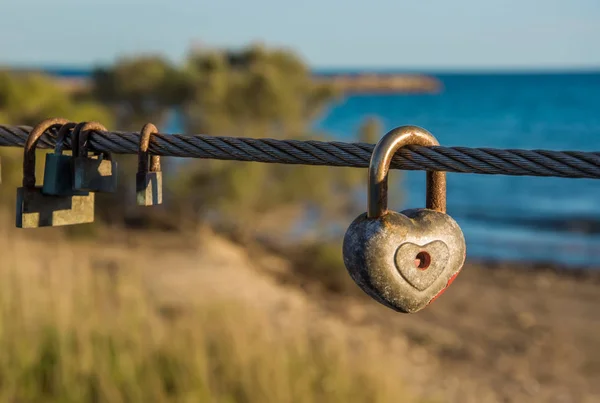 Velhos cadeados enferrujados pendurados na corda da ponte. Símbolo amor . — Fotografia de Stock