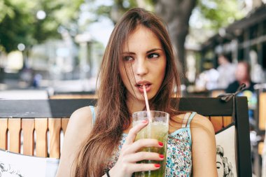 Kadın restoranda kokteyl içiyor. 