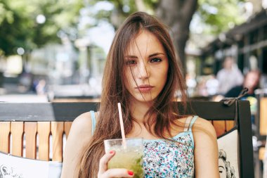 Kadın restoranda kokteyl içiyor. 