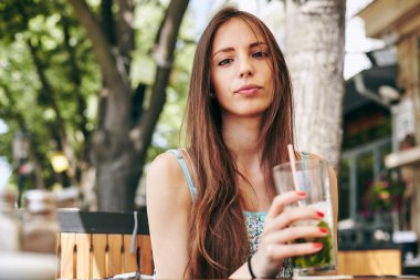 Kadın restoranda kokteyl içiyor. 