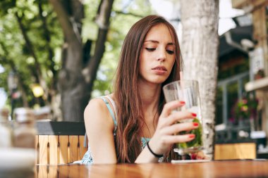Kadın restoranda kokteyl içiyor. 