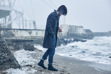 Denize yakın yürüyüş gri paltolu adam