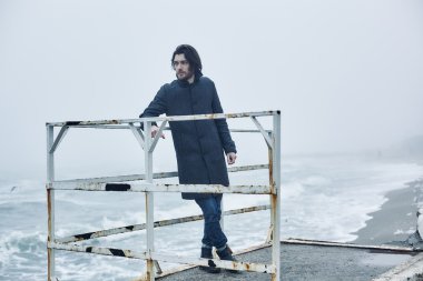 Denize yakın yürüyüş gri paltolu adam