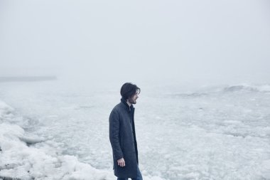 Denize yakın yürüyüş gri paltolu adam