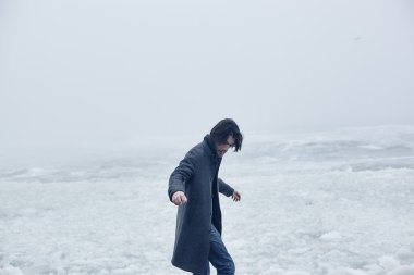 Denize yakın yürüyüş gri paltolu adam