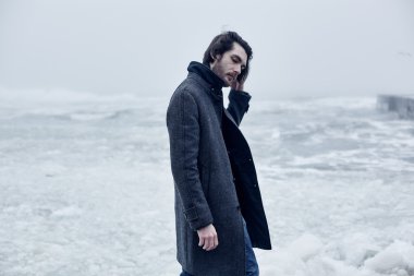 Denize yakın yürüyüş gri paltolu adam