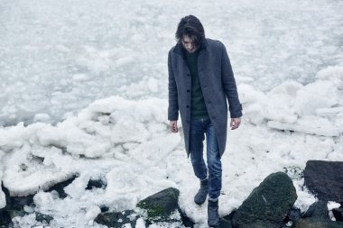 Denize yakın yürüyüş gri paltolu adam