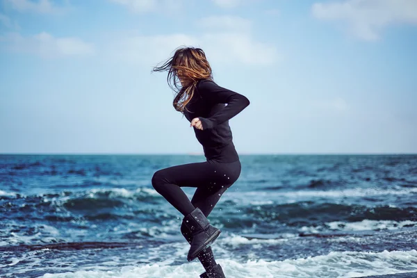 Молодая женщина позирует на скалистом берегу моря — стоковое фото