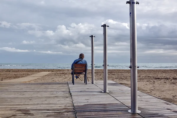 Homme assis sur une chaise au bord de la mer — Photo