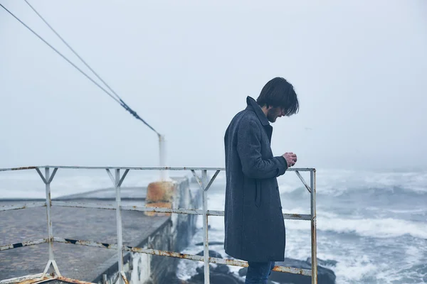 Denize yakın yürüyüş gri paltolu adam — Stok fotoğraf