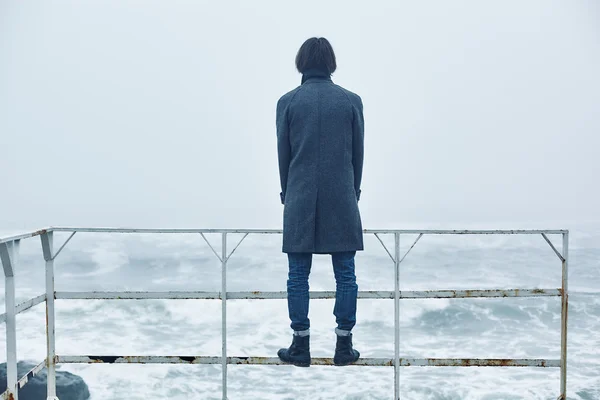 Denize yakın yürüyüş gri paltolu adam — Stok fotoğraf