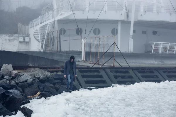 Uomo con un cappotto grigio che cammina vicino al mare — Foto Stock