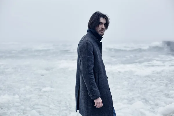 Człowiek w szary płaszcz, chodzenie w pobliżu morza — Zdjęcie stockowe