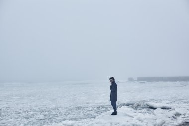 Denize yakın yürüyüş gri paltolu adam