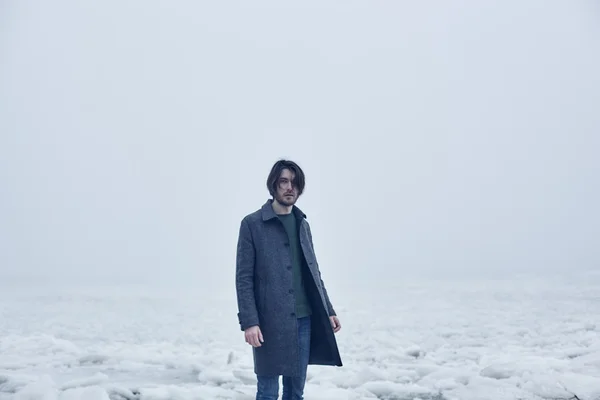 Homme en manteau gris marchant près de la mer — Photo