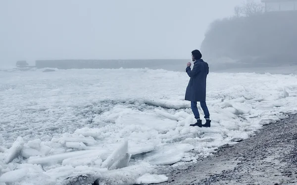 Man i grå jacka gå nära havet — Stockfoto