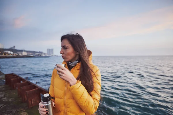 bir termos dolusu çay deniz deniz üzerinde Dawn'la bir sarı ceket aşağı güzel kızla tanışır