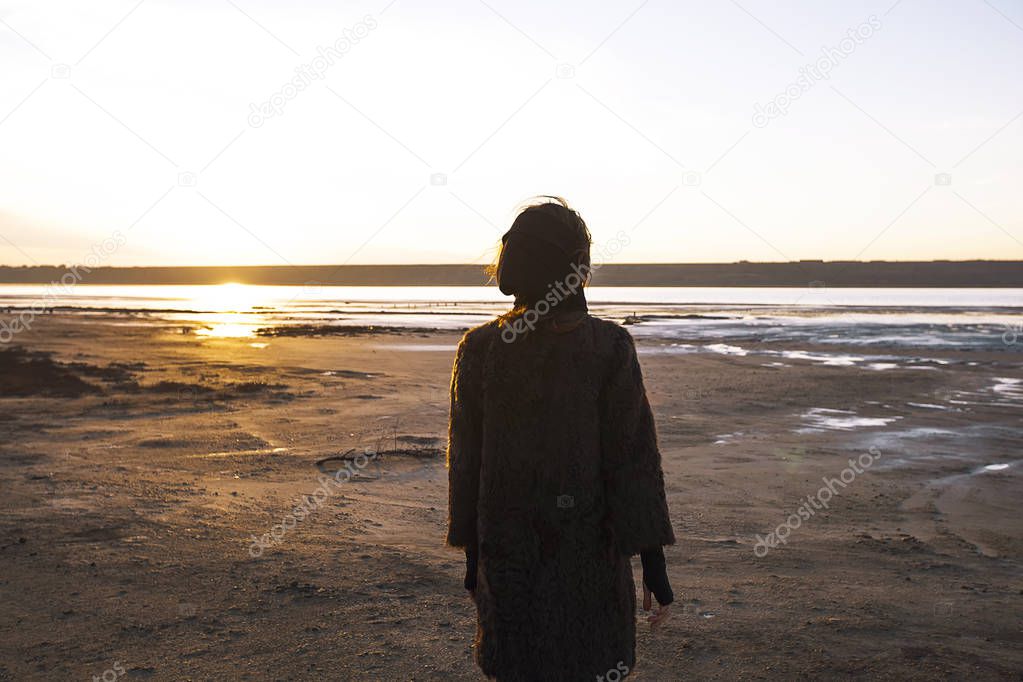 Girl in a coat walks on the lake