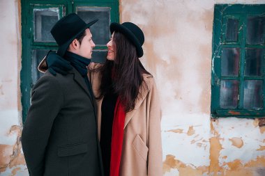 Young hipster beautiful couple in black hats in the winter forest,love,winter vacation in mountains,jeans,warm coat,traveling,hiking,winter walk in love,man in a green coat.girl in a beige coat