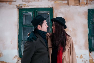 Young hipster beautiful couple in black hats in the winter forest,love,winter vacation in mountains,jeans,warm coat,traveling,hiking,winter walk in love,man in a green coat.girl in a beige coat