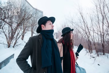 Young hipster beautiful couple in black hats in the winter forest,love,winter vacation in mountains,jeans,warm coat,traveling,hiking,winter walk in love,man in a green coat.girl in a beige coat