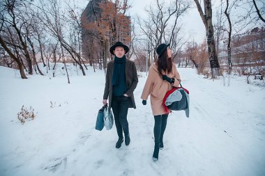 Young hipster beautiful couple in black hats in the winter forest,love,winter vacation in mountains,jeans,warm coat,traveling,hiking,winter walk in love,man in a green coat.girl in a beige coat