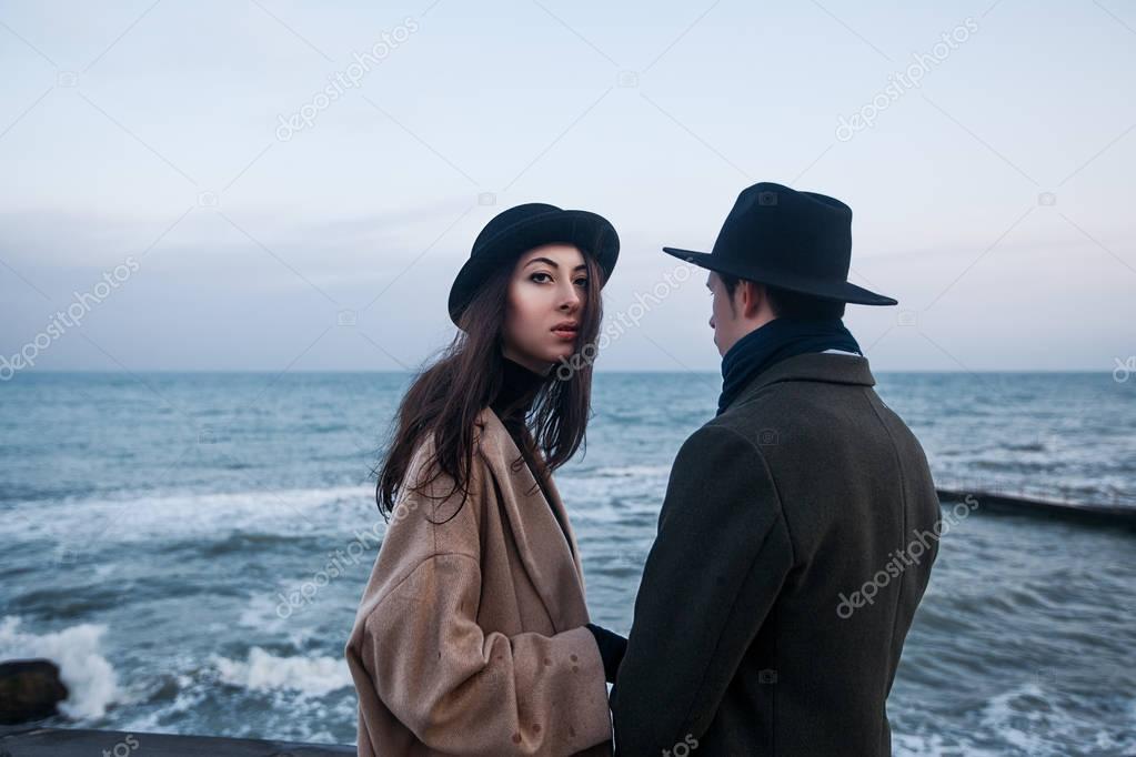 couple in coats and hats standing on terrace