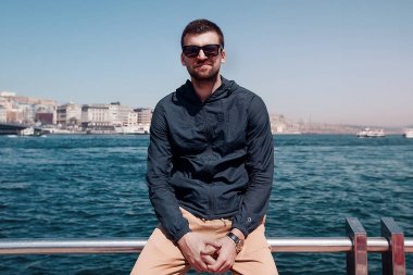 sahil üzerinde oturan güneş gözlüklü adam