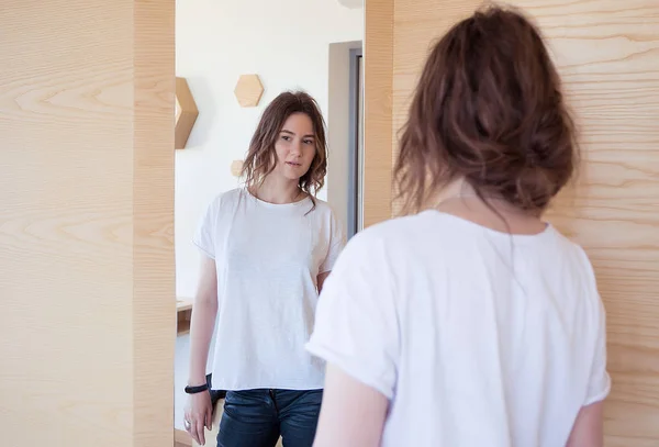 Kvinna med ett lockigt hår som ser att en spegel — Stockfoto