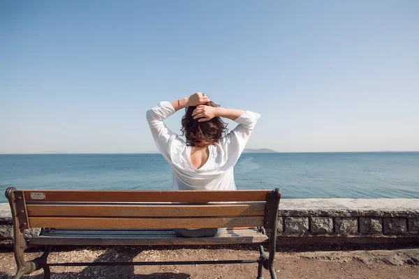 Donna seduta su una panchina al mare — Foto Stock