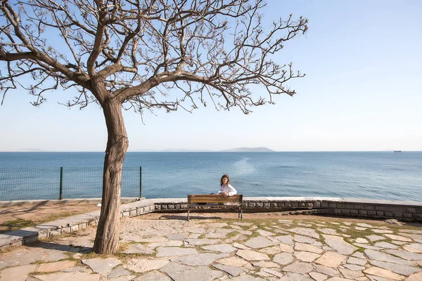 Kobieta siedzi na ławce nad morzem — Zdjęcie stockowe