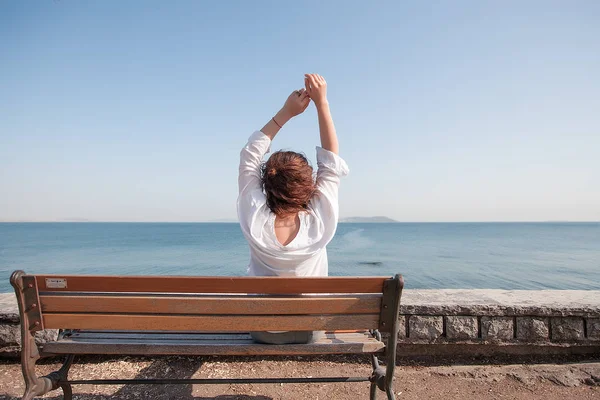Donna seduta su una panchina al mare — Foto Stock