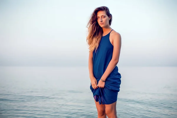 Модель в синем платье позирует на пляже — стоковое фото