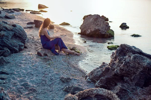 Kvinna sitter på stenig strand — Stockfoto