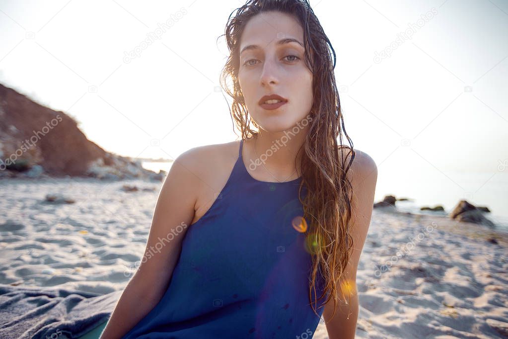woman with wet hair sitting on beach 