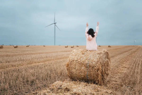 girl in pink raincoat on haystack