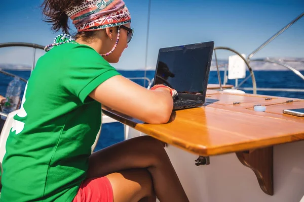 Kvinna med laptop yachting i havet — Stockfoto