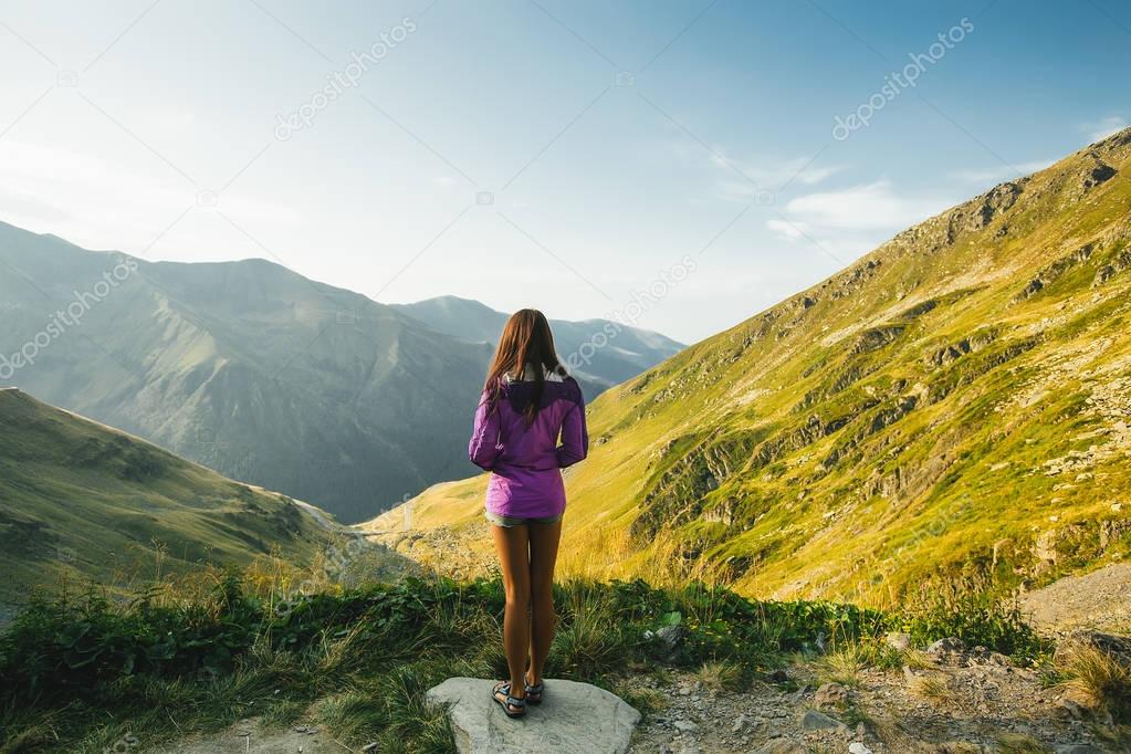 back view of woman standing on beautiful serpentine road and mountains background