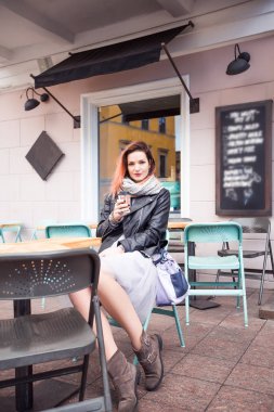 Açık kafede masada oturan genç güzel kadın 