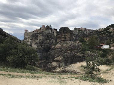 Gündüz vakti ormanla kaplı dağların arasında kayaların tepesine inşa edilen görkemli manzara. 