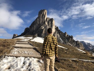 Gündüz vakti karla kaplı dağların arasında poz veren kameralı erkek gezginin arka görüntüsü 