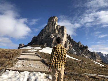 Gündüz vakti karla kaplı dağların arasında poz veren kameralı erkek gezginin arka görüntüsü 