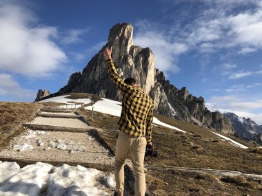 Gündüz vakti karla kaplı dağların arasında poz veren kameralı erkek gezginin arka görüntüsü 
