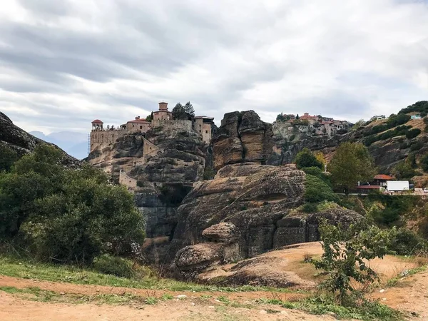 picturesque view of building on top of rock among mountains covered with forest at daytime