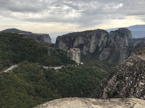 picturesque view of building on top of rock among mountains covered with forest at daytime