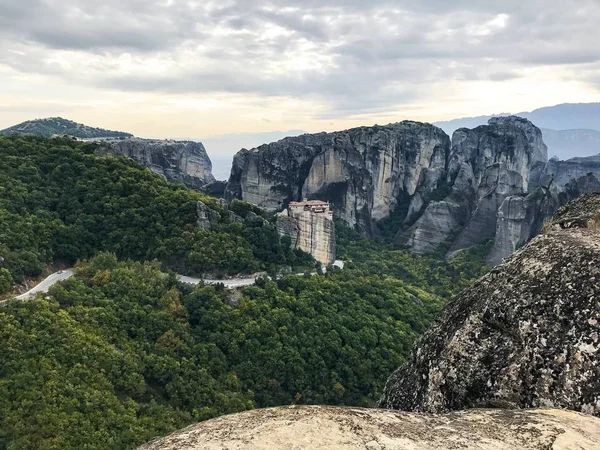 picturesque view of building on top of rock among mountains covered with forest at daytime